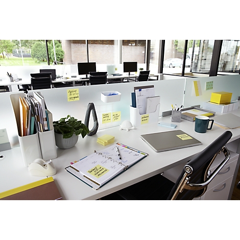 Espace de travail de bureau avec des pense-bêtes, des stylos, un ordinateur portable et des plantes.