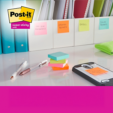 Post-it-Haftnotizen auf Schreibtisch. Gelbe, orange, grüne und pinkfarbene Zettel; daneben Stifte und Handy.