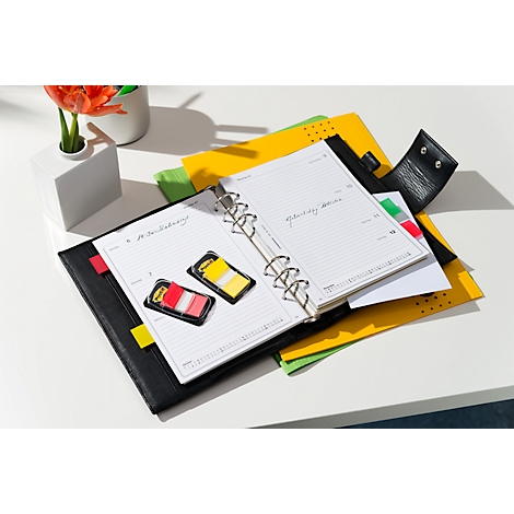 Verschiedene Post-it-Notizen in schwarzen Kunststoffverpackungen. Oben steht "Post-it" auf gelben Schildern.