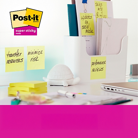 Un bureau avec des notes autocollantes et un support. Il y a des puces sur les notes. En arrière-plan, une pancarte avec Post-it.