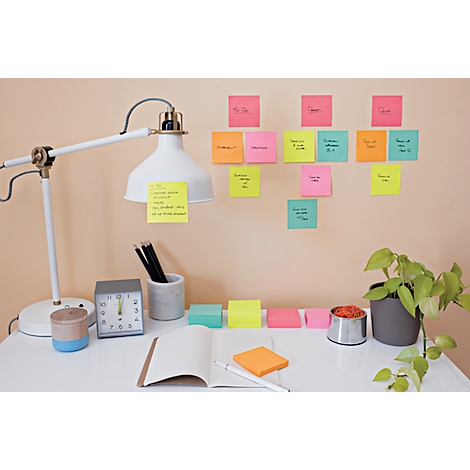Desk with lamp, sticky notes, and plants. Notes on the wall, notepad, and pen are ready.