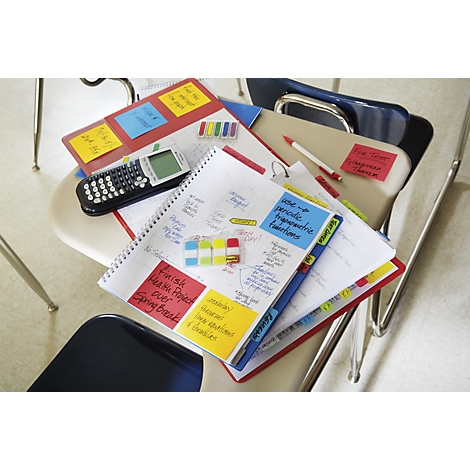 Notebook with notes and post-its, a calculator and pens are on a chair.
