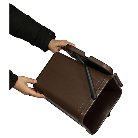 Personne tenant une poubelle marron, couvercle ouvert. Vêtements noirs, fond blanc.