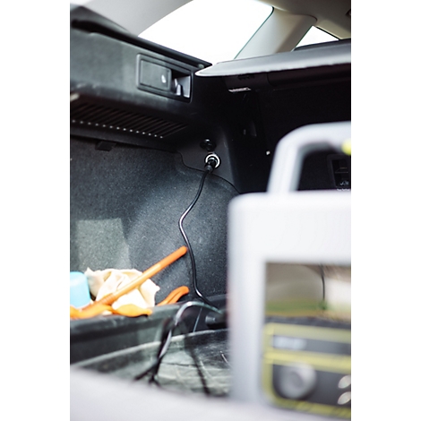 Ein im Kofferraum eines Autos angeschlossenes Ladegerät mit schwarzem Kabel an der 12-Volt-Steckdose.