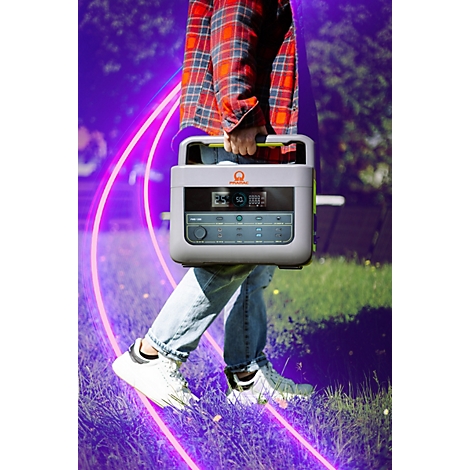 Person trägt eine graue Powerstation mit LCD-Display im Freien vor einem neon-violetten Hintergrund.