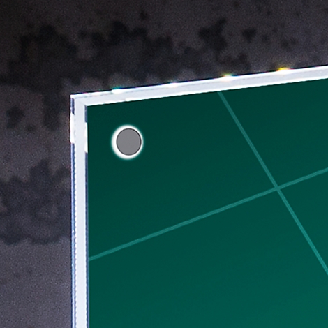 Close-up of a gray circle with a white border on a green surface, surrounded by a white frame and a dark background.