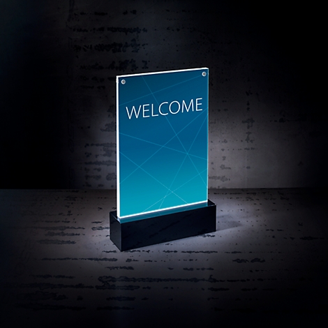 An illuminated sign displaying the word "WELCOME" on a blue backdrop. It is standing on a black base against a dark background.