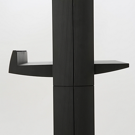 Meuble noir avec une surface nervurée. Deux étagères à angle droit, une à gauche, une à droite.