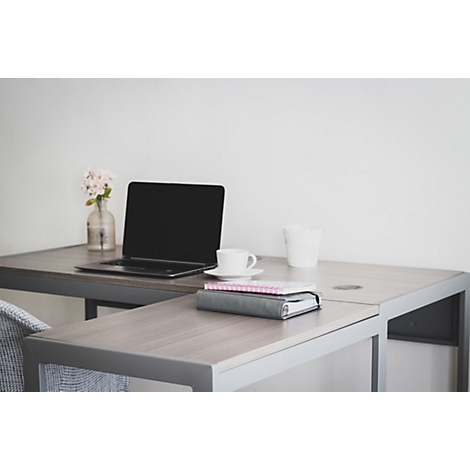 Un bureau élégant avec un ordinateur portable ouvert, une tasse à café blanche et un vase de fleurs. Un classeur est posé sur la table.