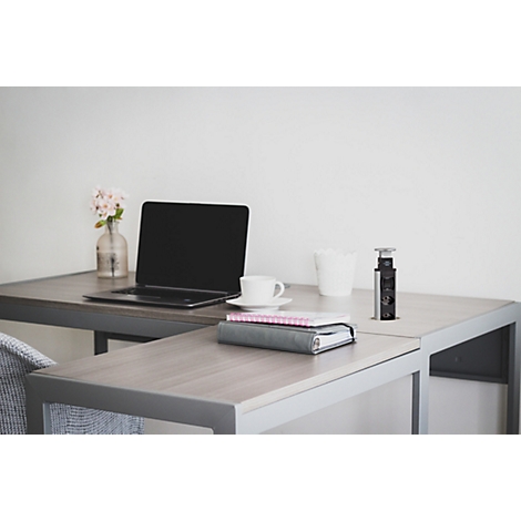 Un bureau moderne avec un ordinateur portable, une tasse à café, un carnet et une plante dans un vase en verre.