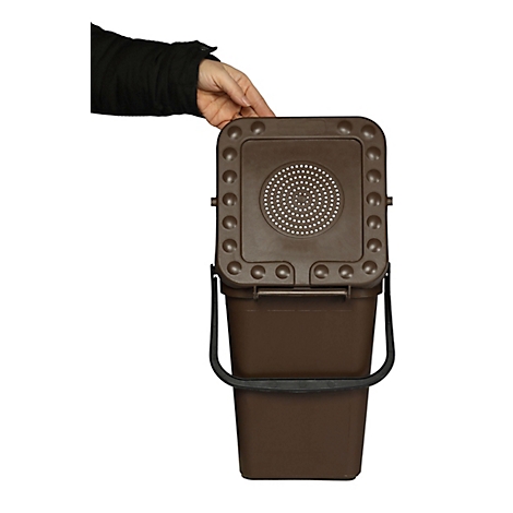 Bruine compostbak met deksel en handvat. Een hand opent het deksel.