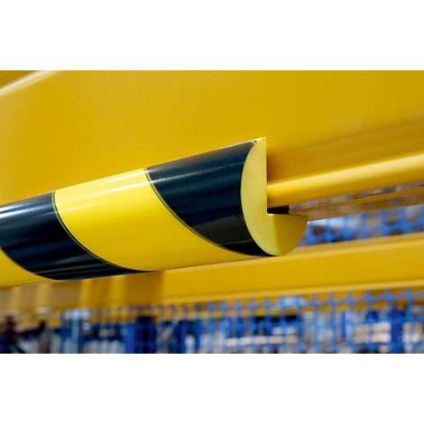 Barre métallique jaune avec des bandes d'avertissement noires et jaunes. Un détail d'un entrepôt.