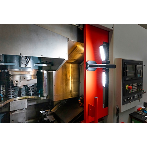 Vue intérieure d'une machine-outil. Zone rouge, pièce à usiner à gauche, panneau de commande à droite.