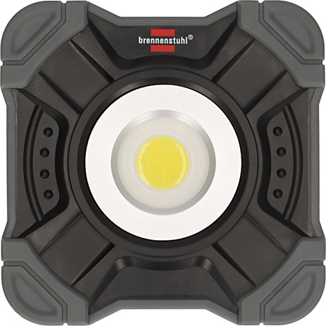 Une main dans un gant gris tient un projecteur LED portable en forme de carré avec une surface lumineuse argentée.