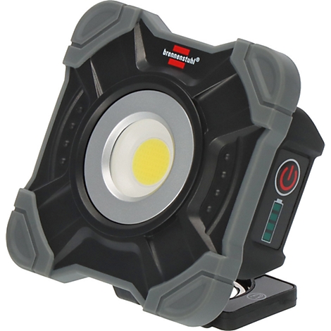 Un homme en vêtements de travail bleus et gants gris tient une lampe de chantier portable. Une échelle se trouve en arrière-plan.