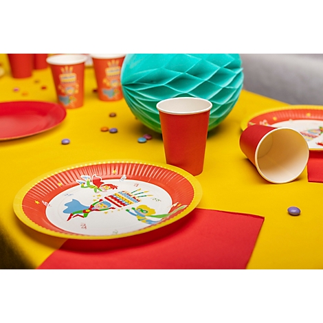 Geburtstagsdekoration, gelber Tisch mit Tellern, Bechern, Tischdecke und Papierkugel.