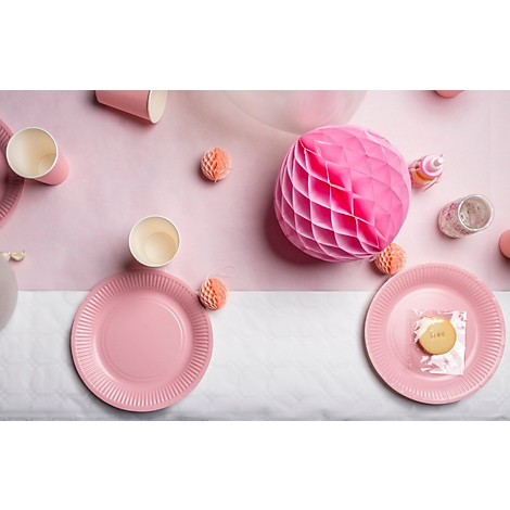 Draufsicht auf einen festlich gedeckten Tisch in Rosa. Teller, Becher und Dekorationen sind zu sehen.