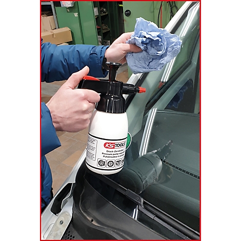 Person reinigt Autoscheibe mit Drucksprüher, Halterung KS TOOLS, blauem Tuch.