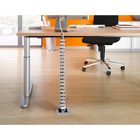 Detail of an office. A cable channel leads to the floor. A desk chair at the table.