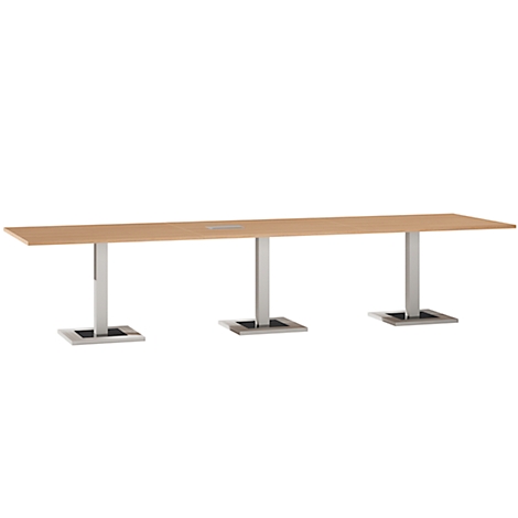 Long conference table with light wood top. Three metal legs, square feet.