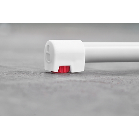 Close-up of the end of a white tube resting on a gray surface. A red knob is visible.