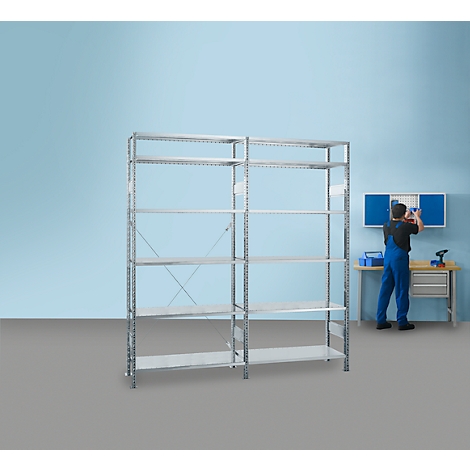 A man is assembling a shelf in a workshop. The shelves are in front of a blue wall. On the right, a man in blue overalls.