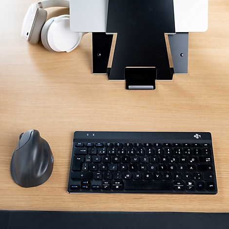 Blick von oben auf einen Schreibtisch mit schwarzem Ständer für ein Tablet, Kopfhörern, einer vertikalen Maus und einer Tastatur.