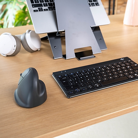 Laptop auf Ständer, ergonomische Maus, Tastatur und Kopfhörer auf einem Holztisch.