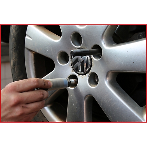 Nahaufnahme einer Hand, die einen Radmutternschlüssel an einem VW-Rad ansetzt.