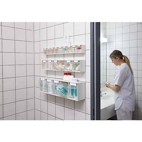 Infirmière se préparant dans une salle de bain avec des fournitures médicales, des étagères.