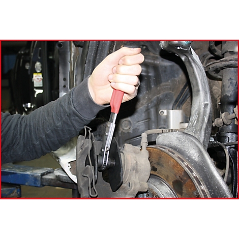 Eine Hand bedient eine Spezialzange an einer Bremsscheibe. Der Fokus liegt auf dem Werkzeug und dem Bremssystem.