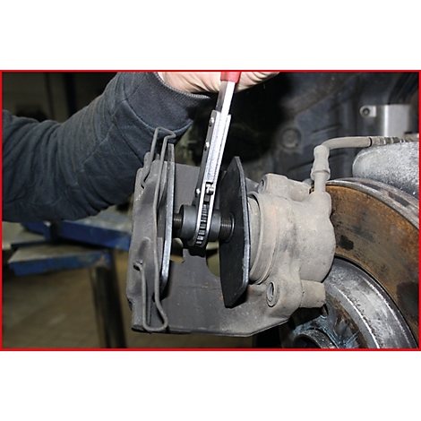 Eine Person benutzt eine Zange, um eine Bremsscheibe an einem Autoreifen zu bearbeiten.