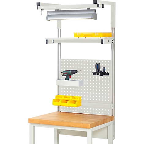 Werkbank mit Werkzeugen, gelben Behältern, Lampe und Lochwand. Auf der Holzplatte steht eine Bohrmaschine.