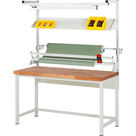 Werkbank mit Holzarbeitsplatte, Rollenhalter, gelben Behältern und Beleuchtung.
