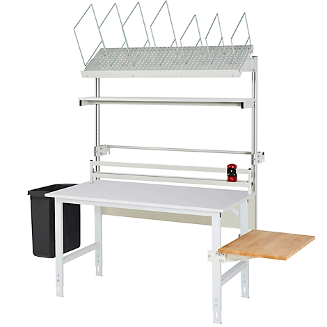 Weißer Packtisch mit diversen Ablagen, Papierrollenhalter und einem kleinen Holzaufleger. Links ein schwarzer Mülleimer.