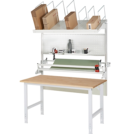 Packstation mit Tisch, Packpapier, Kartons, Werkzeug und Regalen.