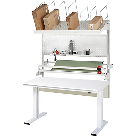 Weißer, höhenverstellbarer Packtisch mit Kartons und Verpackungsmaterial. An der Wand befestigt sind ein Regal, Rollenhalter und Werkzeug.