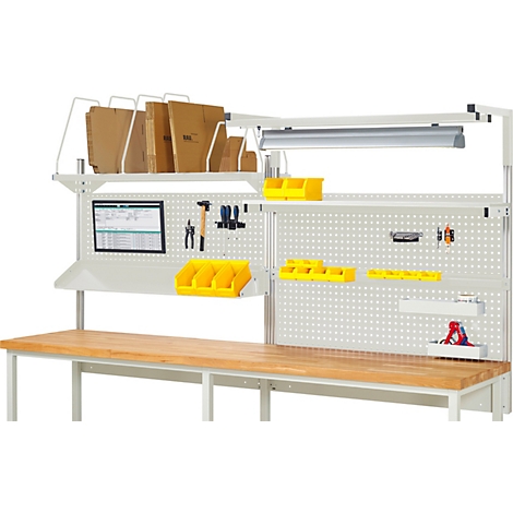 Een werkbank met een houten blad, gereedschap en bakken. Papier op hanglampen. Witte muur met gaten.