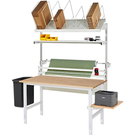 Een werkplek met tafel, schappen voor dozen en papierrollen, en printer en prullenbak.