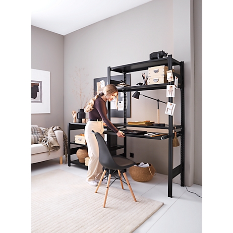 Jeune femme plaçant une chaise devant un bureau noir qui fait partie d'une étagère. L'étagère se trouve dans un salon élégamment meublé.