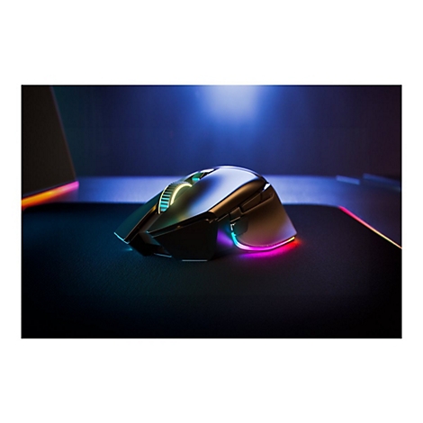 Drahtlose Gaming-Maus mit RGB-Beleuchtung auf schwarzem Mauspad, farbige Lichter. Im Hintergrund ein Laptop.