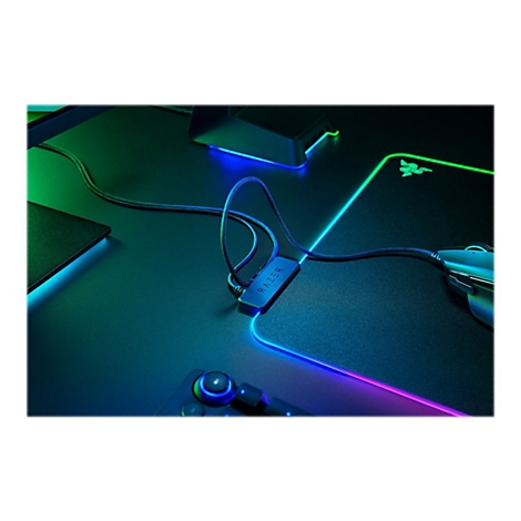 Schreibtisch mit Razer-Maus, Mauspad und Kabelhalter. Das Mauspad leuchtet in Neonfarben.