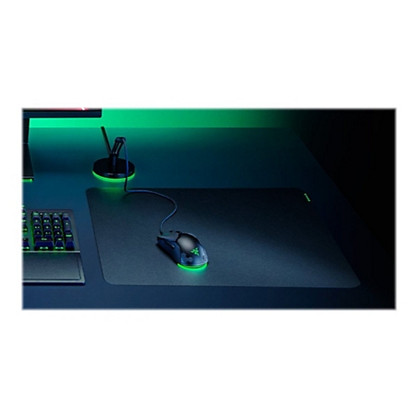 Gaming-Maus mit grün leuchtender Unterbodenbeleuchtung auf einem Mauspad, daneben eine Tastatur und ein Kabelhalter.