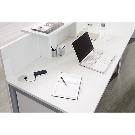 Opgeruimde witte kantoorwerkplek met een laptop, notitieboek en een aangesloten smartphone.