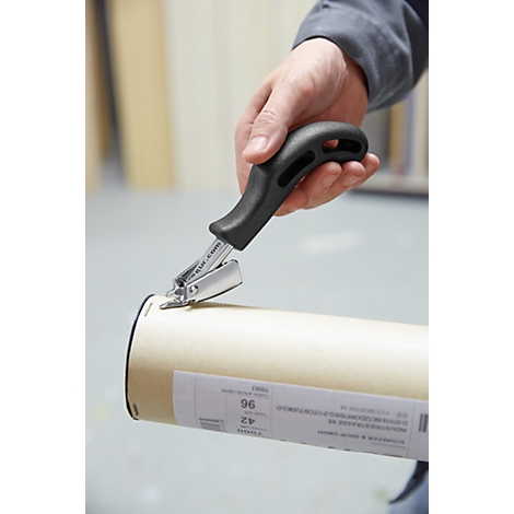 Person securing paper roll with stapler. Hand holds black handle and silver stapling tool.