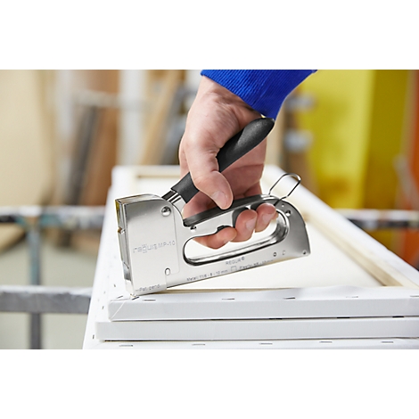 A person using a silver staple gun to attach canvas to a wooden frame.