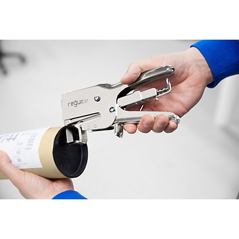 Person staples a cardboard cylinder with a silver stapler. The stapler says 'regus 31'.