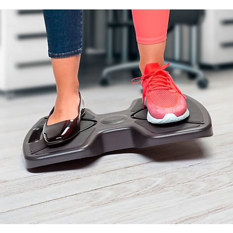 Gros plan sur des pieds sur une plateforme ergonomique. Un pied dans une chaussure noire, l'autre dans une chaussure de sport.
