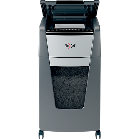 Grey paper shredder with open lid, below is a paper container with shredded paper scraps. The brand name Rexel is visible on the front.