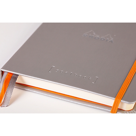 Cahier gris avec marque-page et élastique orange, marque Rhodia. L'impression "notebook" est visible.